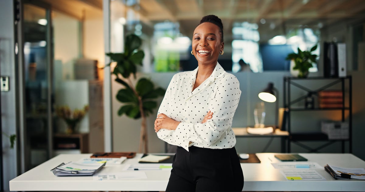 Confident Black woman entrepreneur with arms crossed, smiling, representing the accomplished leaders Her Digital Moments works with